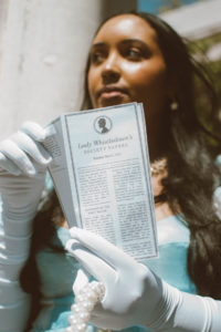 Girl wearing a Bridgerton inspired outfit, Selkie Ritz Gown with white elbow length gloves and regencycore hairstyle