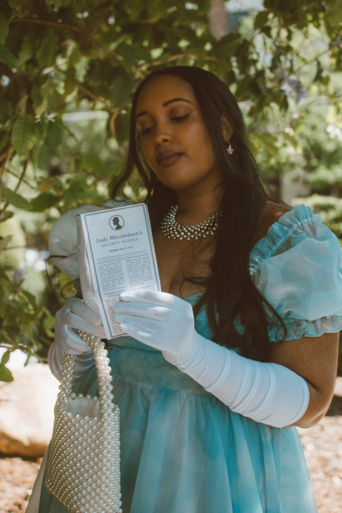 Girl wearing a Bridgerton inspired outfit, Selkie Ritz Gown with white elbow length gloves and regencycore hairstyle