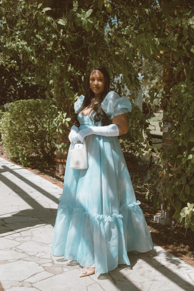 Girl wearing a Bridgerton inspired outfit, Selkie Ritz Gown with white elbow length gloves and regencycore hairstyle