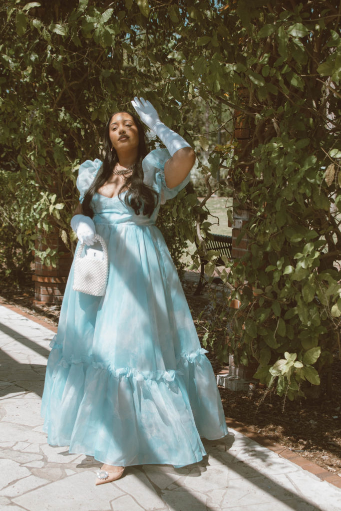 Girl wearing a Bridgerton inspired outfit, Selkie Ritz Gown with white elbow length gloves and regencycore hairstyle