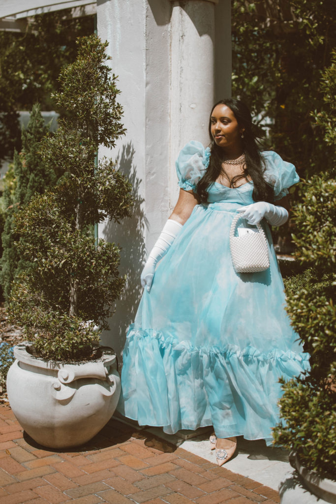 Girl wearing a Bridgerton inspired outfit, Selkie Ritz Gown with white elbow length gloves and regencycore hairstyle