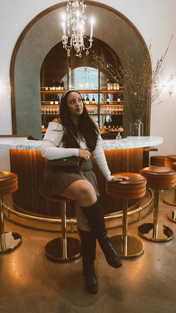 Girl sitting at the art deco inspired bar at Le Bon Nosh located in the Buckhead neighborhood of Atlanta.