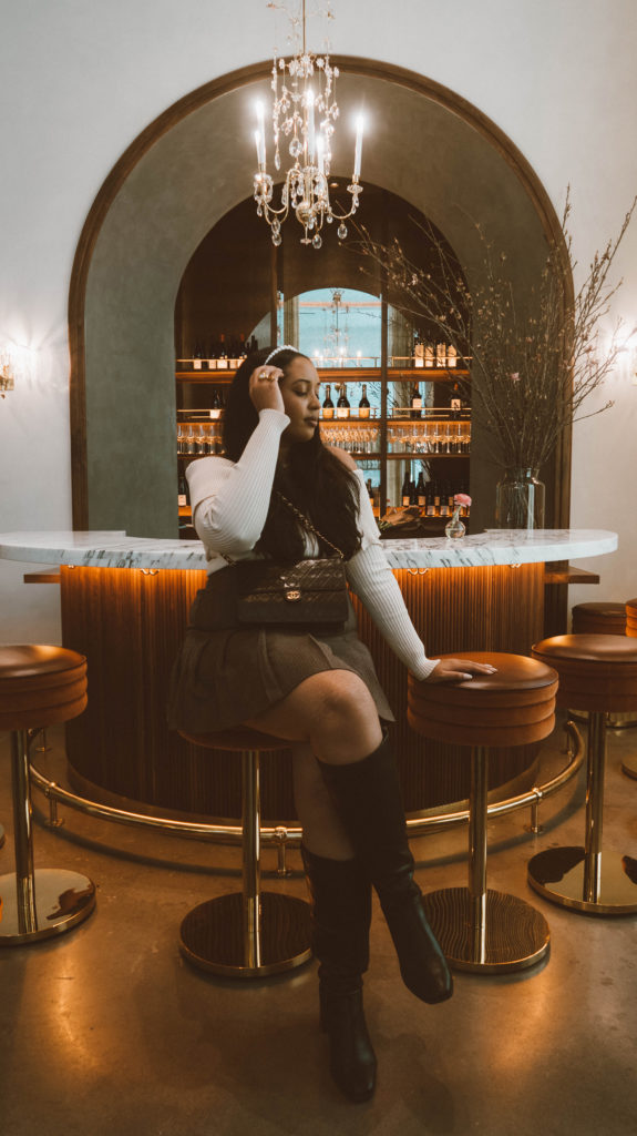 Girl sitting at the art deco inspired bar at Le Bon Nosh located in the Buckhead neighborhood of Atlanta.